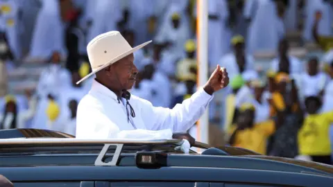 Yoweri Museveni waves to crowd from vehicle sunroof during inauguration